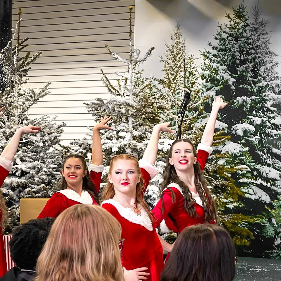 West End Kids performers in festive costumes dancing in front of snowy Christmas trees