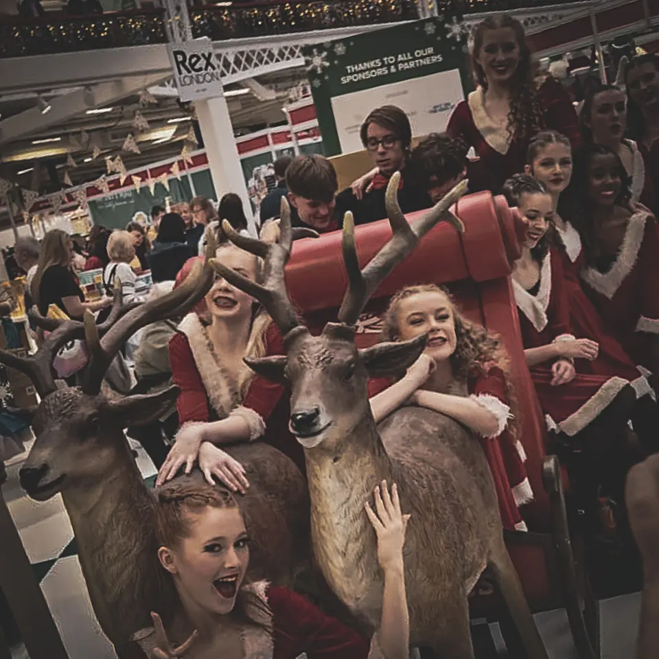 West End Kids performers in festive costumes with model reindeer and a sleigh at the Ideal Home Show