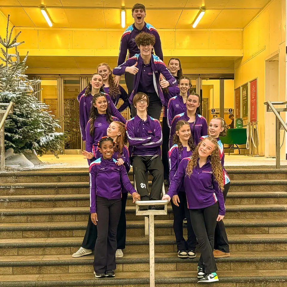 The West End Kids troupe in purple team jackets posing on the steps outside a venue
