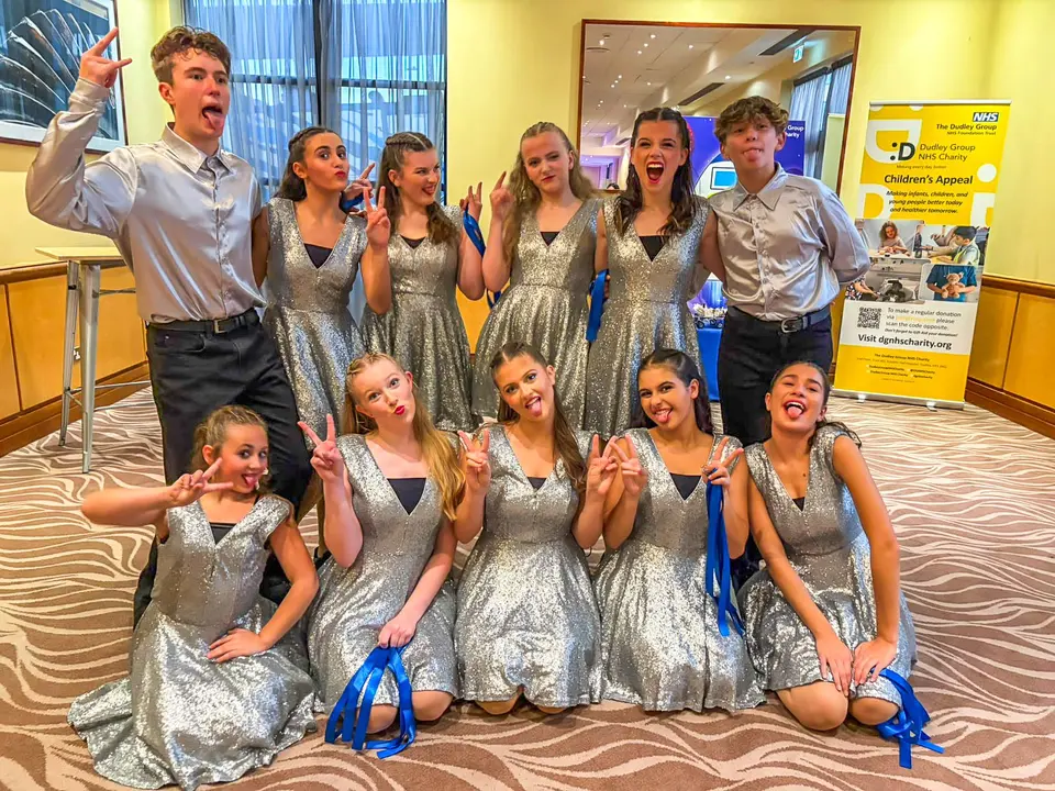 Eleven West End Kids performers in silver sequin dresses and satin shirts, pulling playful faces and pulling peace signs at the Copthorne Hotel in Dudley